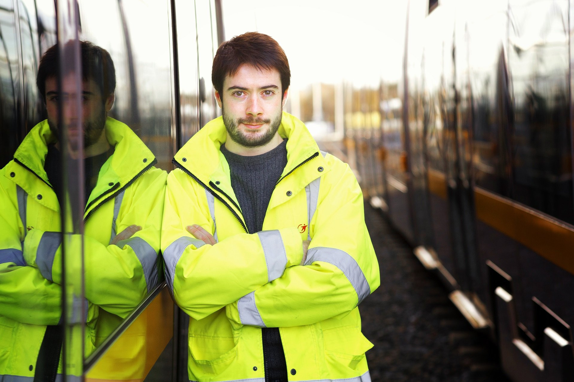 Homme en gilet jaune adossé à un tramway