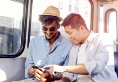 Deux jeunes hommes assis dans un bus regardent un smartphone