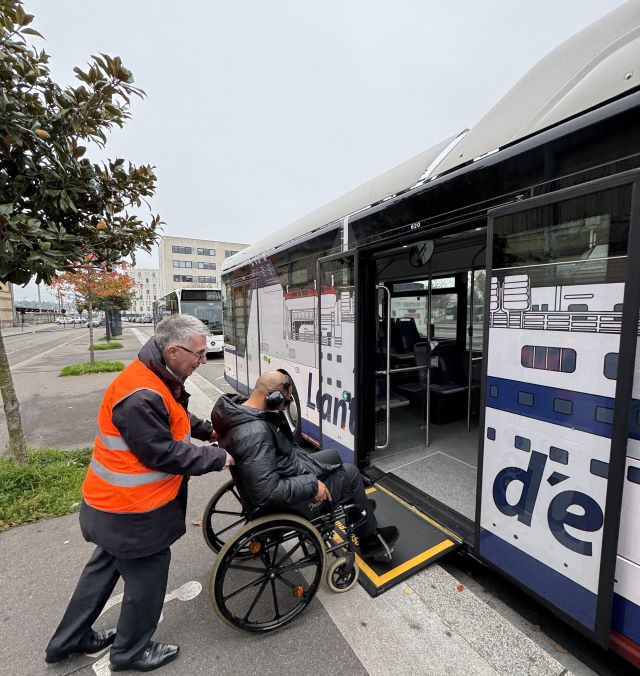 Le Havre - Homme fait monter une personne assise en fauteuil roulant dans un bus LIA