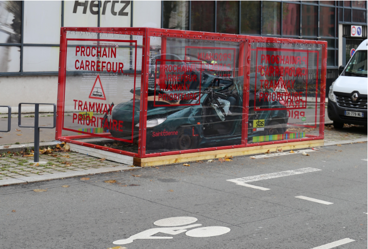 Voiture gravement accidentée exposée dans un cadre de verre sur la voie publique